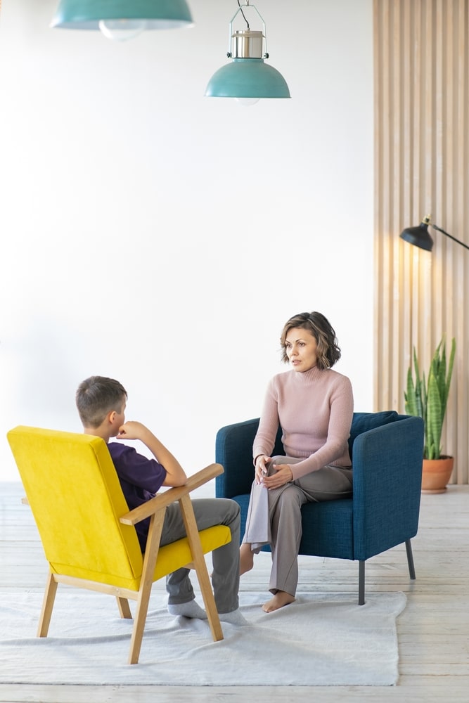 A teen talks to a therapist during a therapy session.
